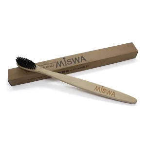 Brosse à dents en bambou MISWA aux poils noirs, devant son étui kraft