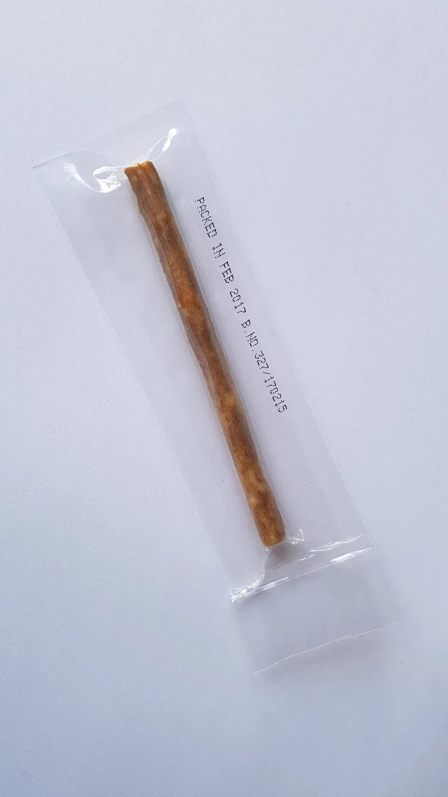 Un siwak humide emballé sous vide dans un sachet plastique transparent, avec une date d'emballage imprimée